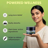 Woman holding a jar of Pain Relief Balm with 'Powered Wellness' branding and product benefits listed.