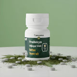 White bottle labeled 'Cannama Trailokya Vijaya Vati' with green label on a white surface with scattered pills and green leaves, against a light green background.